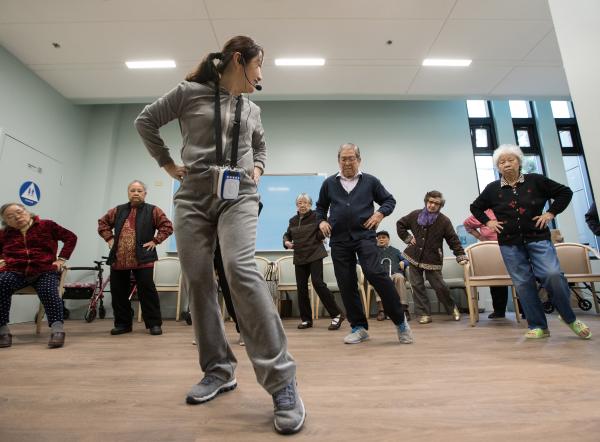 A group of Asian seniors practice Tai Chi 