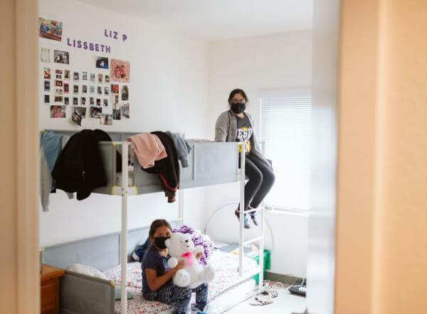 Two young girls sit on their bunk bed